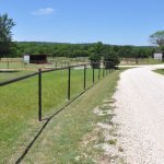 A fenced in area with grass and trees.