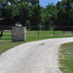 A gravel road leading to a fenced in area.