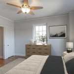 A bright bedroom with a beige bed, black and beige bedding, a wooden dresser, a window, framed art, a ceiling fan, and two open doors. Light walls and a potted plant create a clean, modern look.