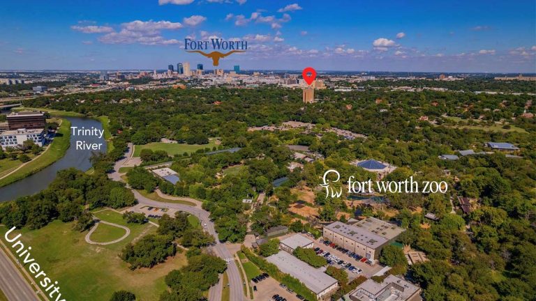 Aerial view of Fort Worth, Texas, showing the Fort Worth Zoo, Trinity River, and city skyline in the distance under a blue sky, with labeled landmarks and a red location pin on a tall building.