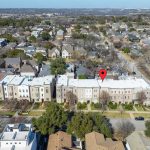 Aerial view of a suburban neighborhood with rows of houses and trees; a red location pin marks one building in the center.
