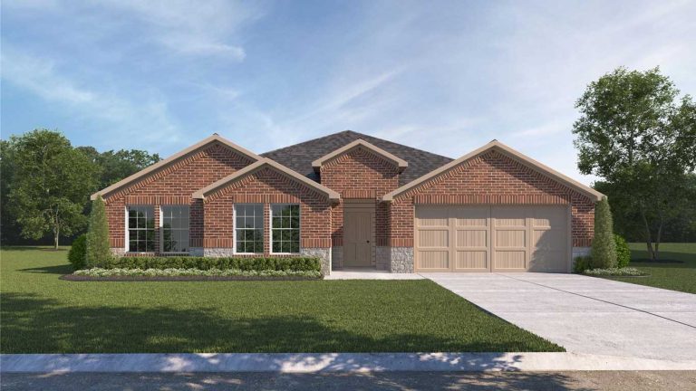 Single-story brick house with tan trim and a double garage, set on a manicured lawn with shrubs and trees. A wide driveway leads to the garage, and the sky is clear with a few clouds.